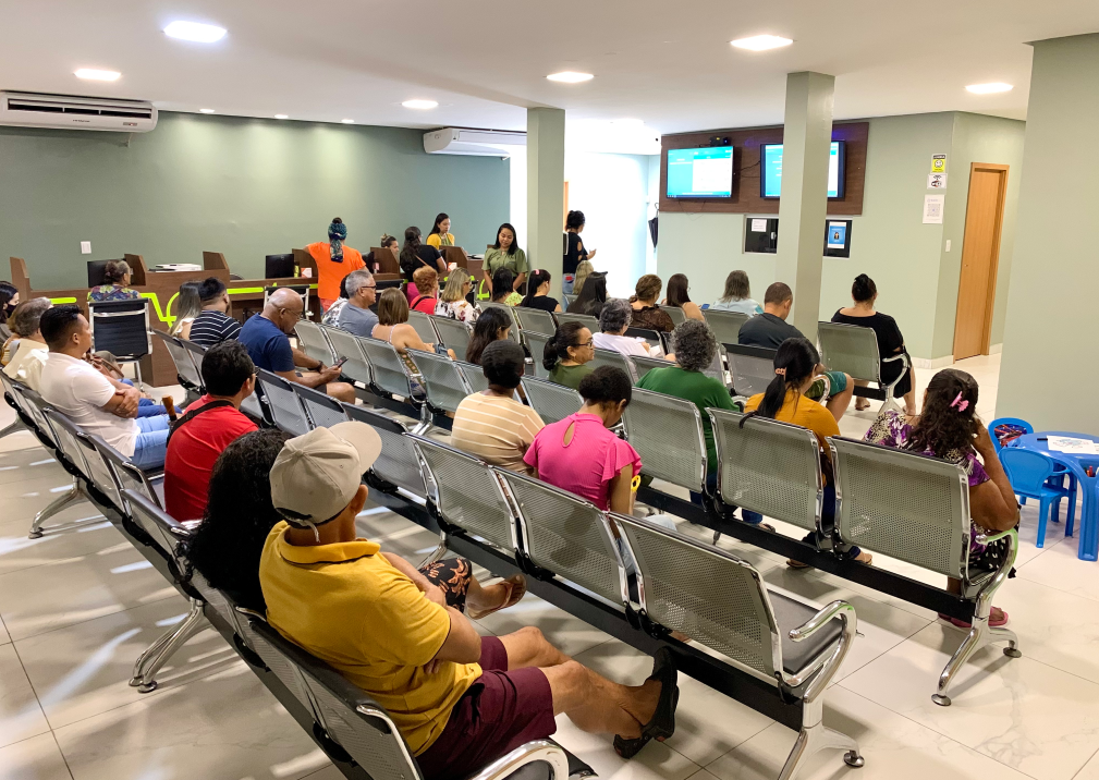 Recepção ampla com cadeiras e TVs, com pacientes aguardando